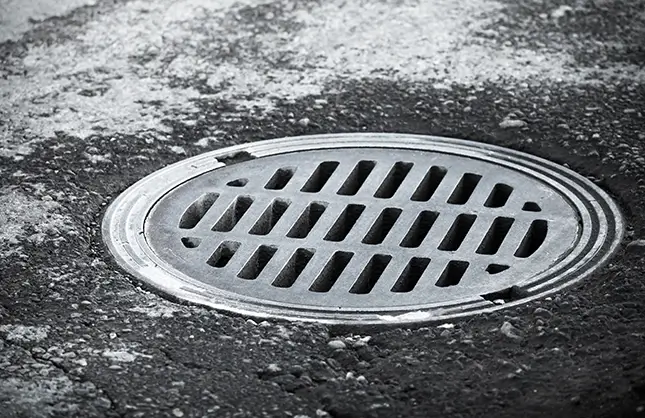 Sewer manhole on the urban asphalt road. Closeup photo